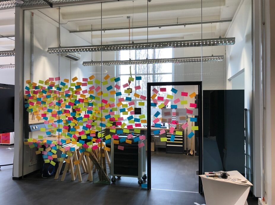 Beispiel Glaswand einer Maker Garage mit bunten Notizzetteln beklebt