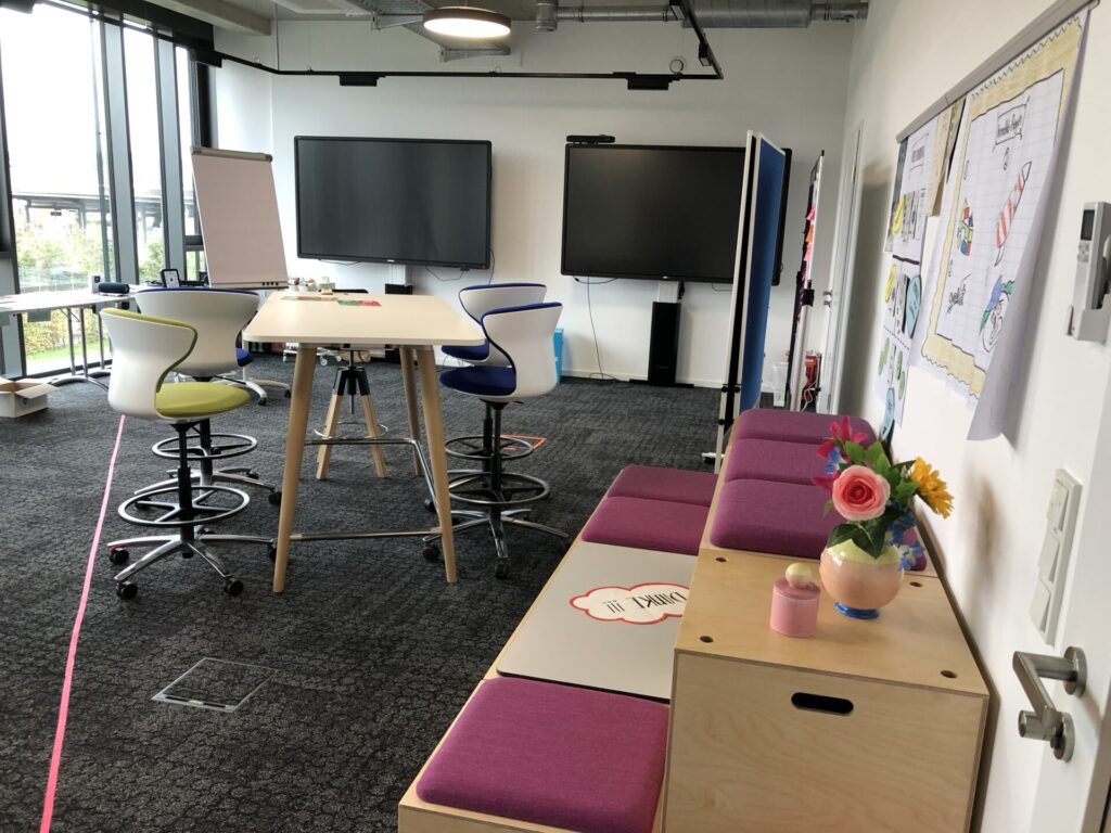 Beispiel Kreativraum mit Gruppentisch, Sitztribüne, Tafeln und Bildschirmen